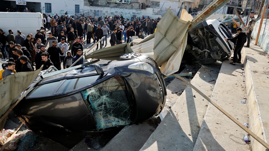 Palestinians inspect damaged vehicles following an Israeli raid in Jenin on Jan 26, 2023.
