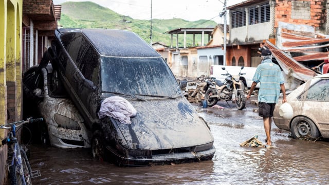 Floodwater, an upturned car and ruined buildings