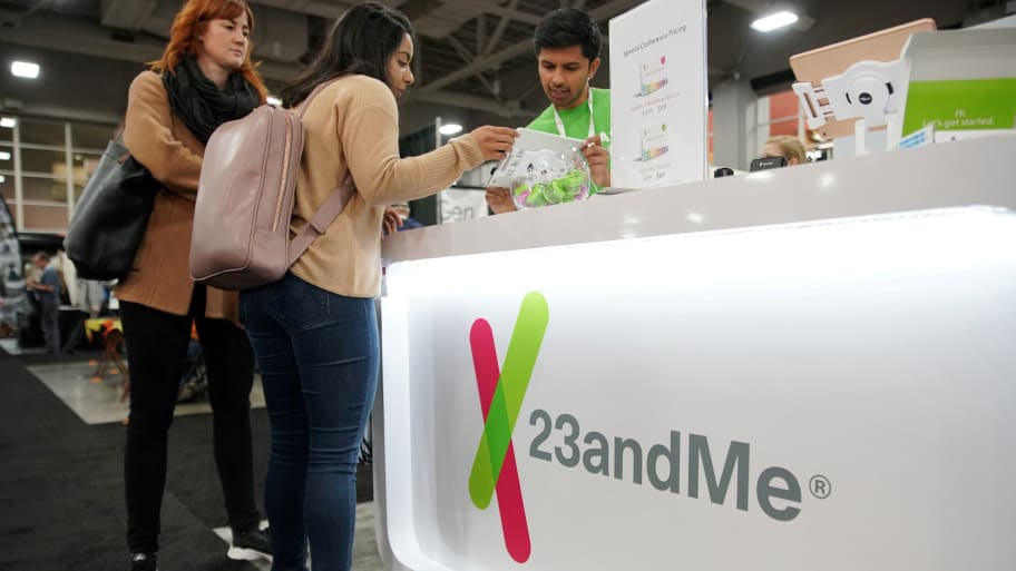 People speak at a 23andMe branded stand.