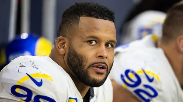 Aaron Donald stares to his right as he sits on the bench in uniform during an NFL game.