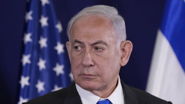 Israeli Prime Minister Benjamin Netanyahu looks on, pictured before flags.