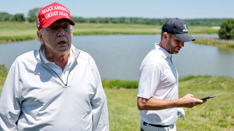 Donald Trump talks with reporters as he and his son Eric Trump participate in the Pro-Am tournament.