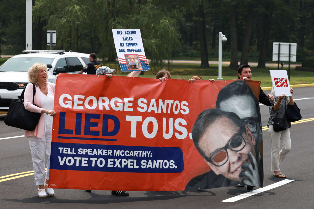 An anti-George Santos protest, with people holding a sign reading, “George Santos Lied to Us.”