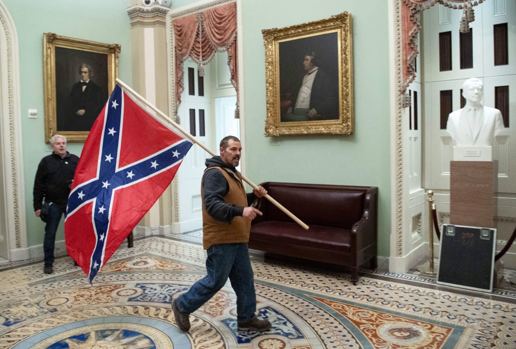 A supporter of US President Donald Trump carries a  Confederate flag as he protests in the US Capitol Rotunda on January 6, 2021, in Washington, DC.