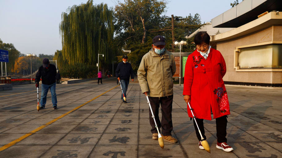 Elderly people practise Chinese calligraphy on the ground at a park in Beijing, China November 10, 2022. 