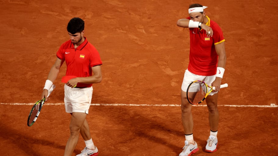 Carlos Alcaraz of Spain and Rafael Nadal walk on a clay court.