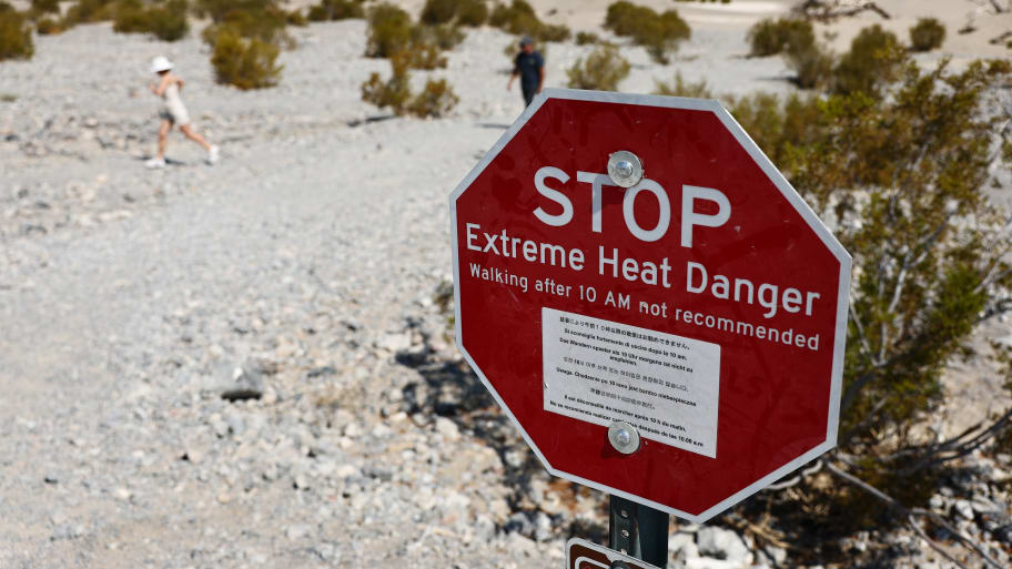 Visitors walk near a 'Stop Extreme Heat Danger' sign at Mesquite Flat Sand Dunes in Death Valley National Park, California. 