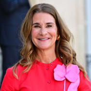 Melinda French Gates, pictured in a red dress appointed with a pink flower.