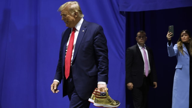 Former President Donald Trump holding a pair of gold Trump-branded shoes