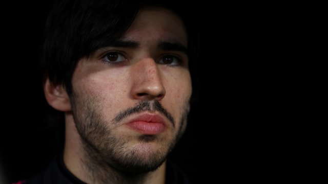 Sandro Tonali stares forward from the bench area at a soccer match.