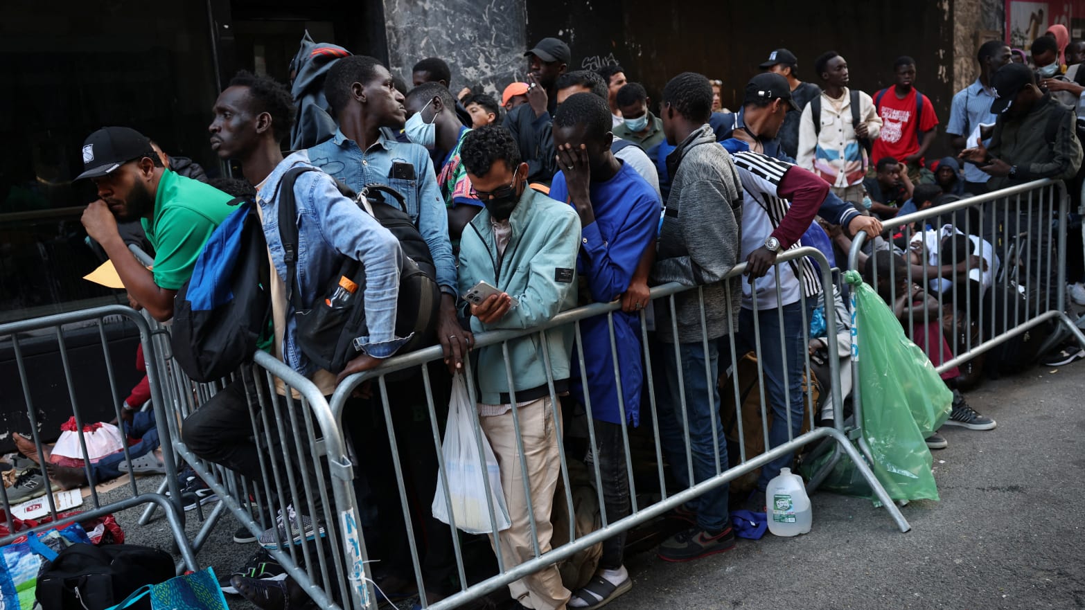 Recently arrived migrants to New York City wait on the sidewalk outside of the Roosevelt Hotel