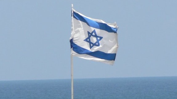 Flag of Israel with the Mediterranean sea in the background.