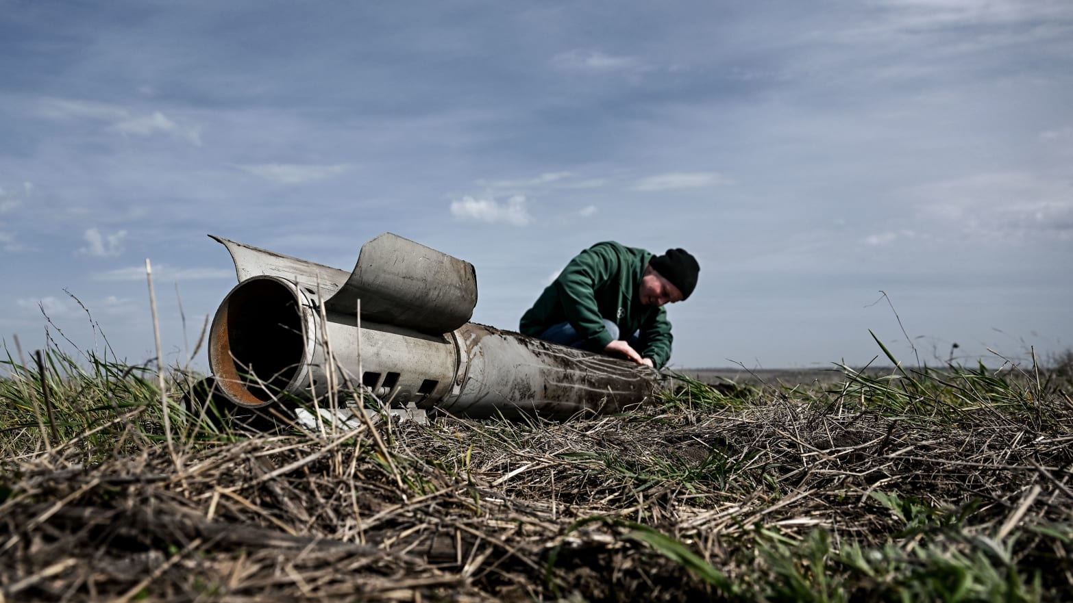 A photograph of a farmer examining a Russian rocket pulled out of the ground during a sowing campaign in southeastern Ukraine on April 18, 2023.