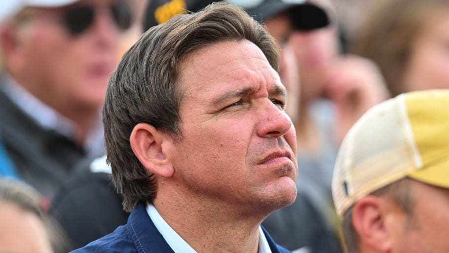 Ron DeSantis stares forward in the stands at a college football game.