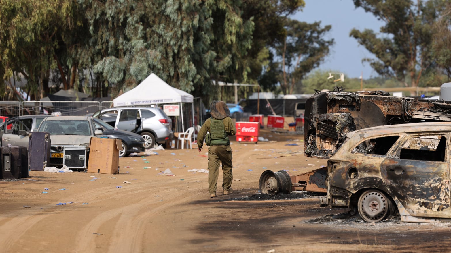 An Israeli soldier walks past burned vehicles at the site of the weekend attack on the Supernova desert music festival by Palestinian militants near Kibbutz Reim.