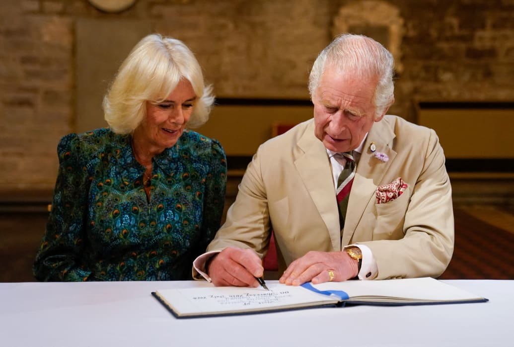 Britain's King Charles and Queen Camilla sign the visitors' book during a visit to Brecon Cathedral, Wales, July 20, 2023.