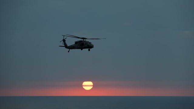 A MH-60R Seahawk of The Swamp Foxes HSM-74 approaches the flight-deck of the USS Dwight D. Eisenhower (CVN 69) aircraft carrier during evening flight-operation in Southern Red Sea, Middle East