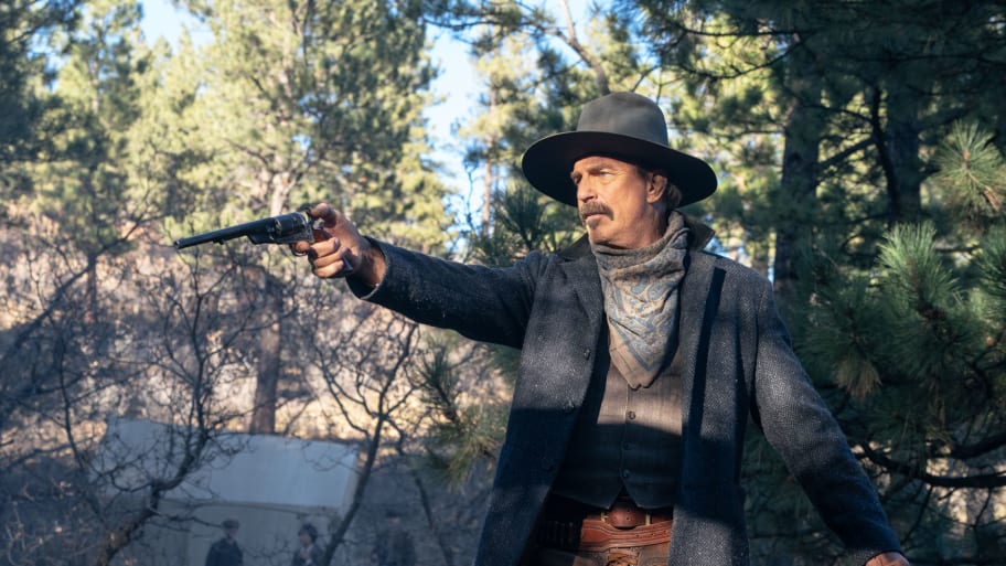 Kevin Costner in Western clothes points a gun