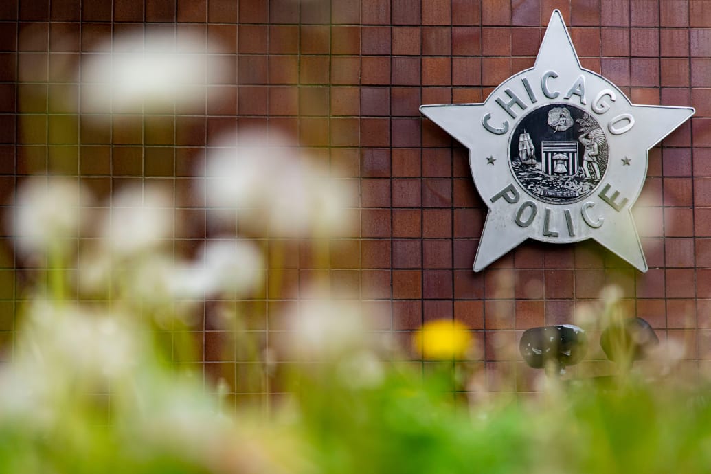 A photo of the exterior of a Chicago police station, with a CPD sign in the shape of a five-pointed police badge affixed to a brick wall.
