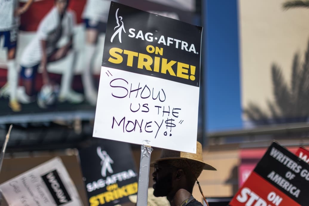 A photo including members of the Hollywood actors SAG-AFTRA union walk a picket line with screenwriters outside of FOX Studios.