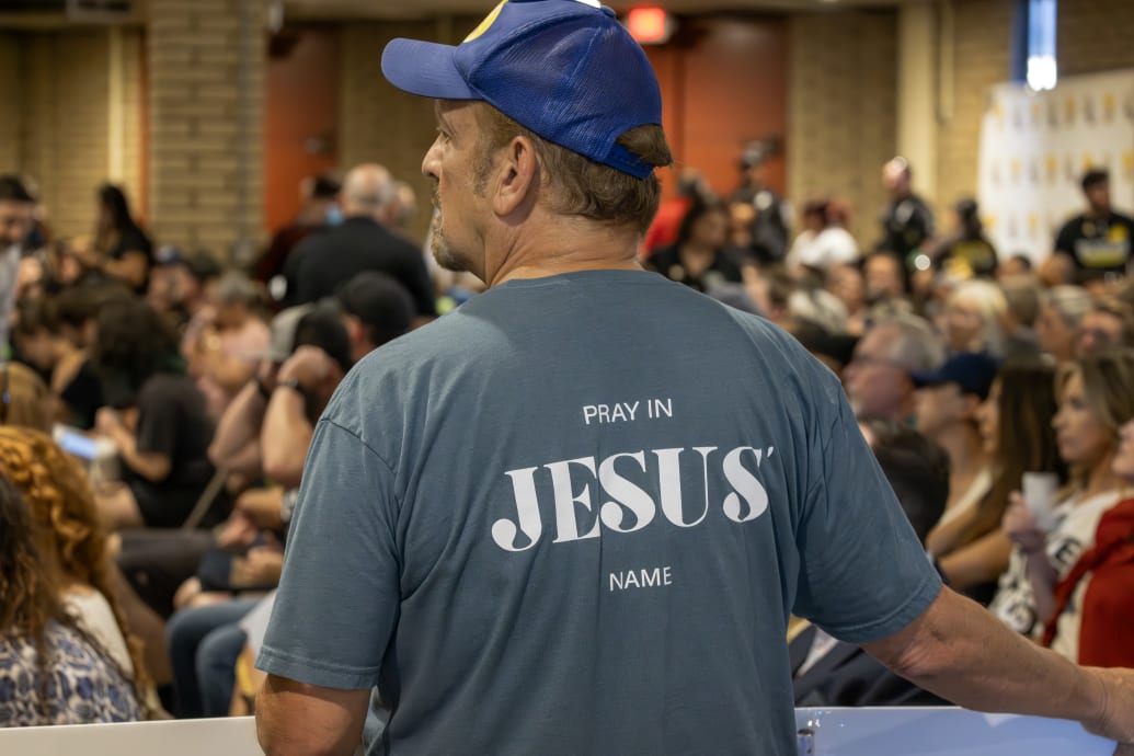  A man wears an evangelical t-shirt and holds a banner in support of a policy that the Chino Valley school board is meeting to vote on which would require school staff to "out" students to their parents.