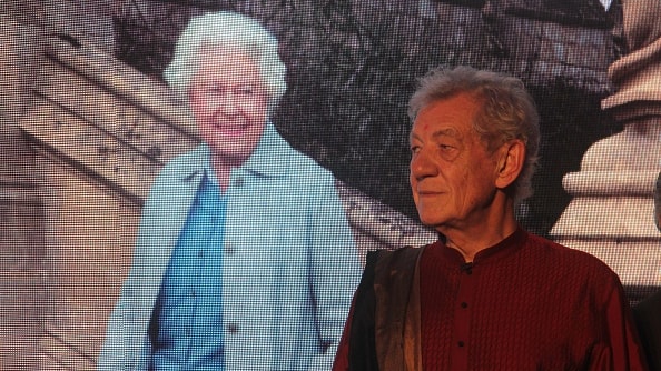 Ian McKellen (L) stands next to a life-sized image of a smiling Queen Elizabeth II