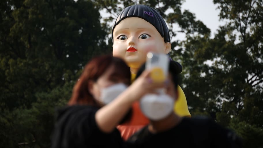 A couple takes a selfie with a giant doll named Younghee from Netflix series “Squid Game” on display at a park in Seoul, South Korea, Oct. 26, 2021.
