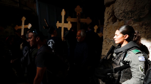 A member of the Israeli police force stands by as worshippers carry crosses during a Good Friday procession along the Via Dolorosa in Jerusalem's Old City April 22, 2022. 