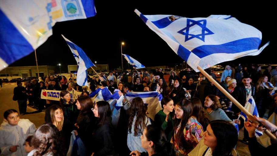 People wave Israeli flags following the release of hostages who were seized during the October 7 attack by Palestinian militant group Hamas