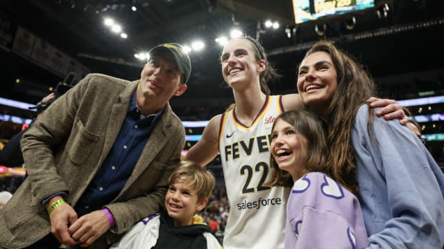 Caitlin Clark #22 of the Indiana Fever poses for a photo with Ashton Kutcher and Mila Kunis after defeating the Los Angeles Sparks
