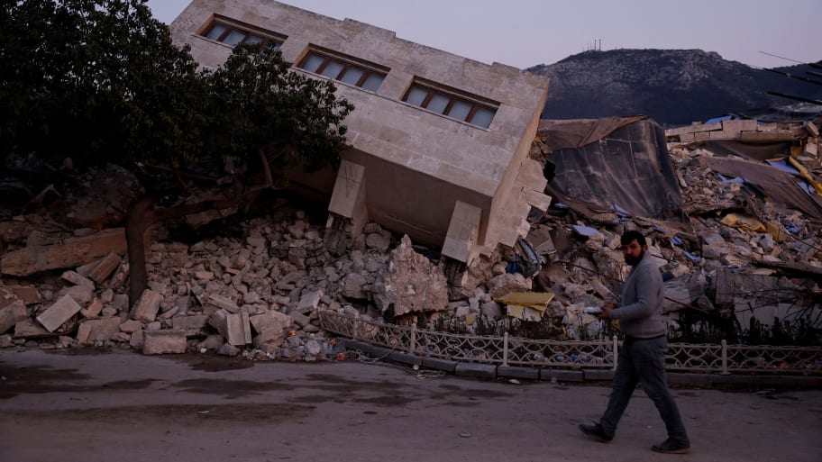 A man walks by a collapsed building and rubble, in the aftermath of a deadly earthquake, in Antakya, Hatay province, Turkey, Feb. 21, 2023. 
