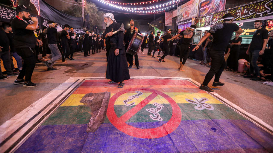 Shiite Muslim devotees self-flagellate over an unfurled banner on the ground depicting the Pride rainbow flag defaced with a boot and the Arabic slogan "no to homosexual society" in the city of Nasiriyah in Iraq on July 25, 2023.