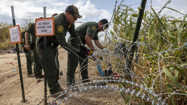 U.S. Border Patrol agents cut an opening through razor wire on the banks of the Rio Grande in Texas. 