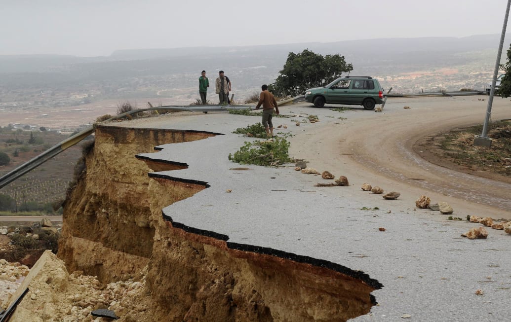 People stand on a damaged road as a powerful storm and heavy rainfall hit Shahhat city, Libya, Sept. 11, 2023. 