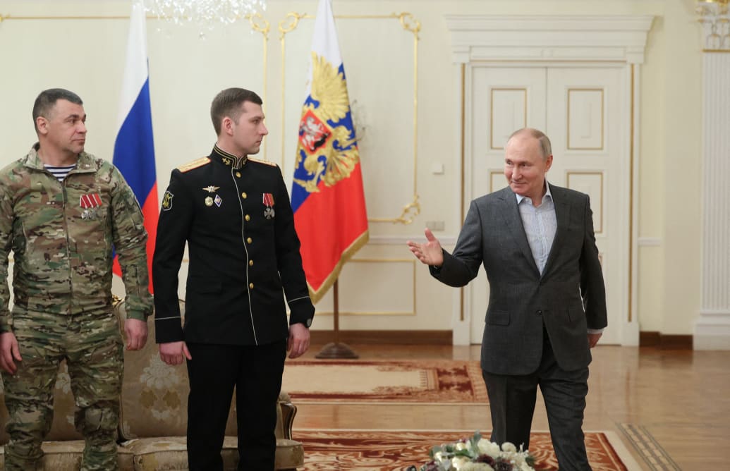 A photo including Russia's President Vladimir Putin with service members 
