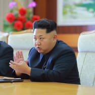 North Korean leader Kim Jong Un sitting down at a table.