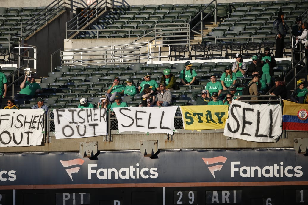 Oakland A’s fans display signs demanding John Fisher sell the team.