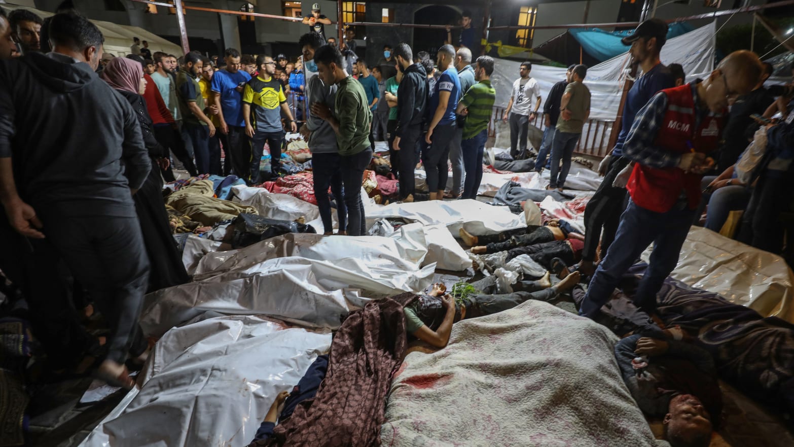 People gather around bodies of Palestinians killed in Israeli airstrikes on the Ahli Arab hospital in central Gaza after they were transported to Al-Shifa hopsital.