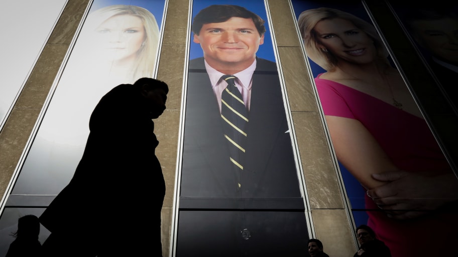 People pass by a promo of Fox News host Tucker Carlson on the News Corporation building in New York, U.S., March 13, 2019.