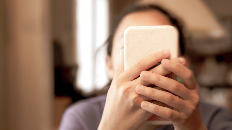 Young girl holding smartphone up to face.