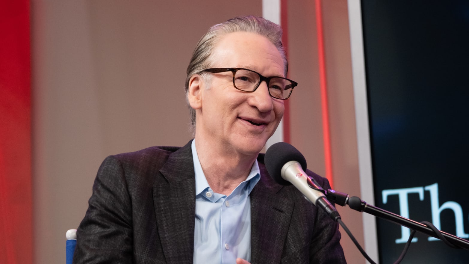 Bill Maher sitting in front of a microphone