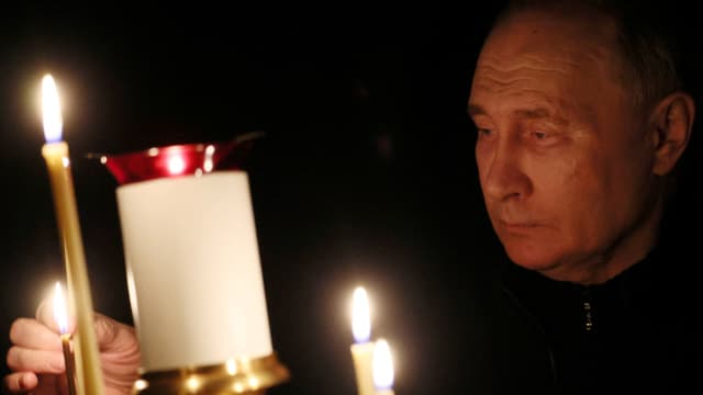 Russian President Vladimir Putin lights a candle in up close picture.