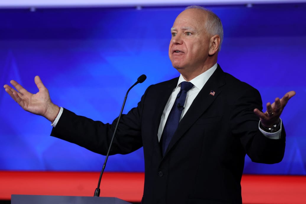 Tim Walz speaks during a televised debate with his arms raised