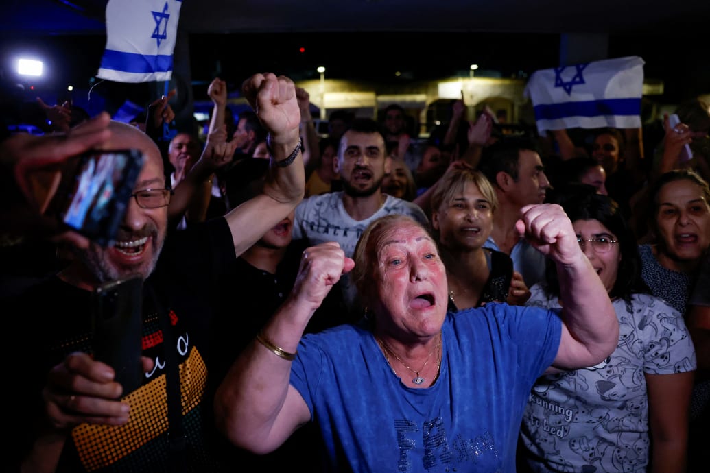 A woman yells with her hands up in celebration with others after the release of Ori Megidish.