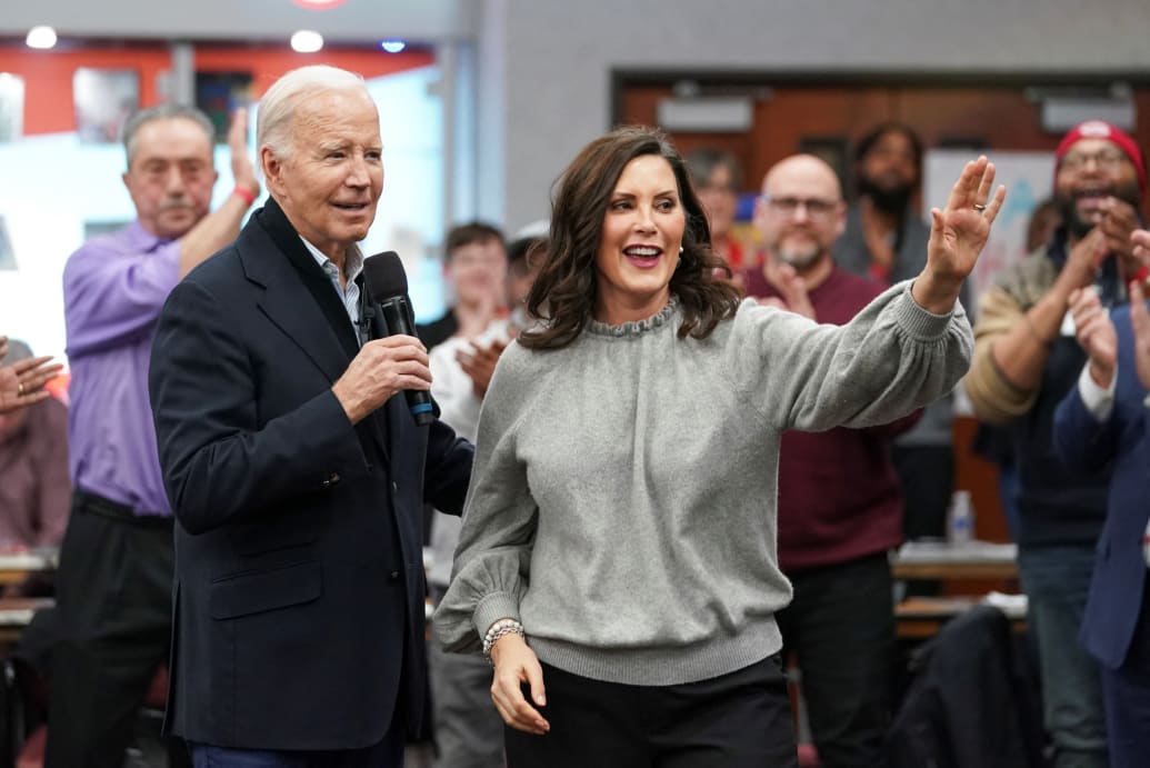 Joe Biden and Michigan Gov. Gretchen Whitmer stand together in front of a clapping crowd.
