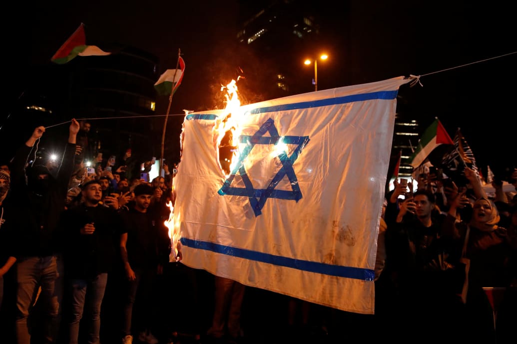 A makeshift Israeli flag is set ablaze in Istanbul, Turkey, outside an Israeli consulate.