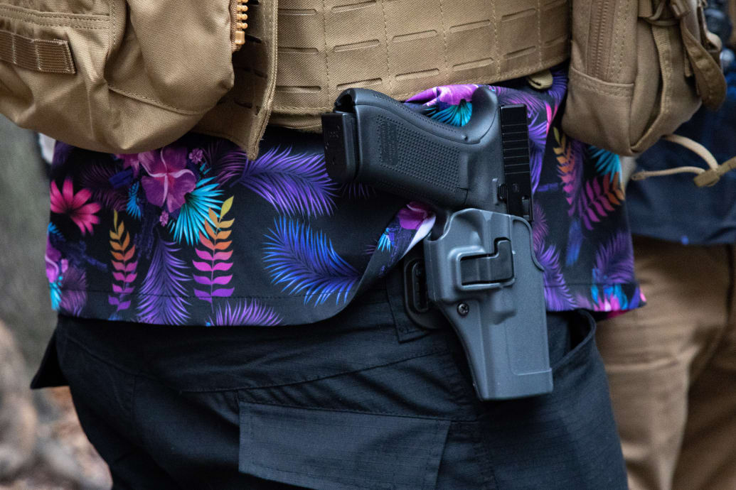 A photo of a Boogaloo Boi wearing a Hawaiian shirt and a gun on his hip.