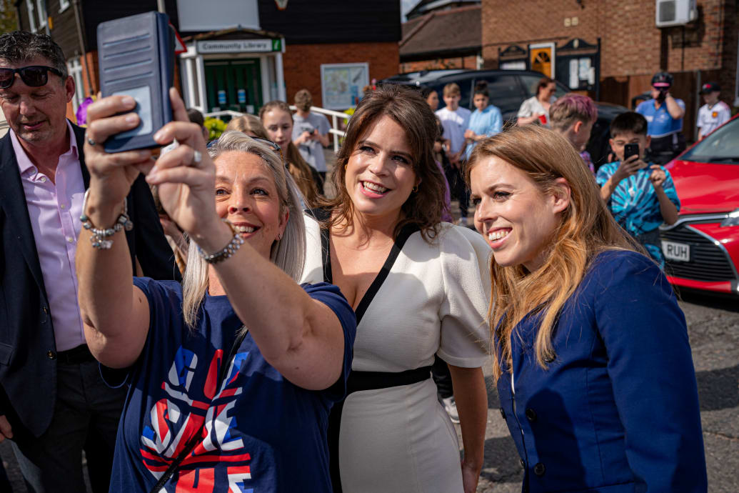 Princess Beatrice (right) and Princess Eugenie (centre) pose for a selfie as they attend the Coronation Big Lunch last year.
