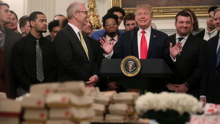 Donald Trump speaks behind a stack of McDonald’s hamburgers.