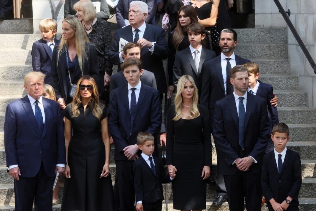 Don Jr. standing in a row of people behind Eric and Barron Trump